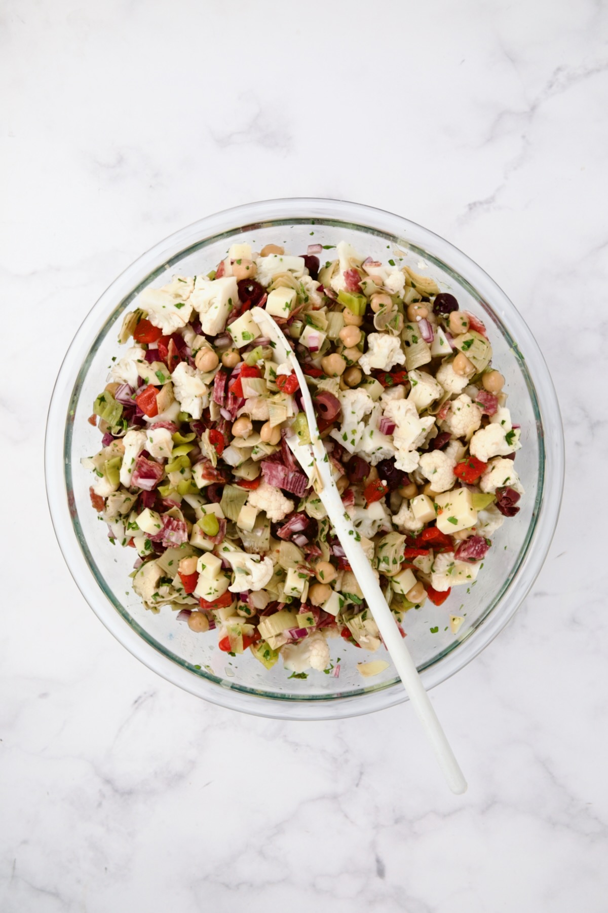 Ingredients for Cauliflower Antipasto Salad in glass bowl after being stirred together.
