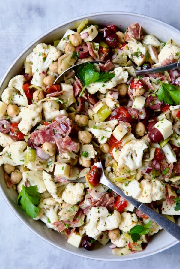 Cauliflower Antipasto Salad in serving bowl with serving utensils.