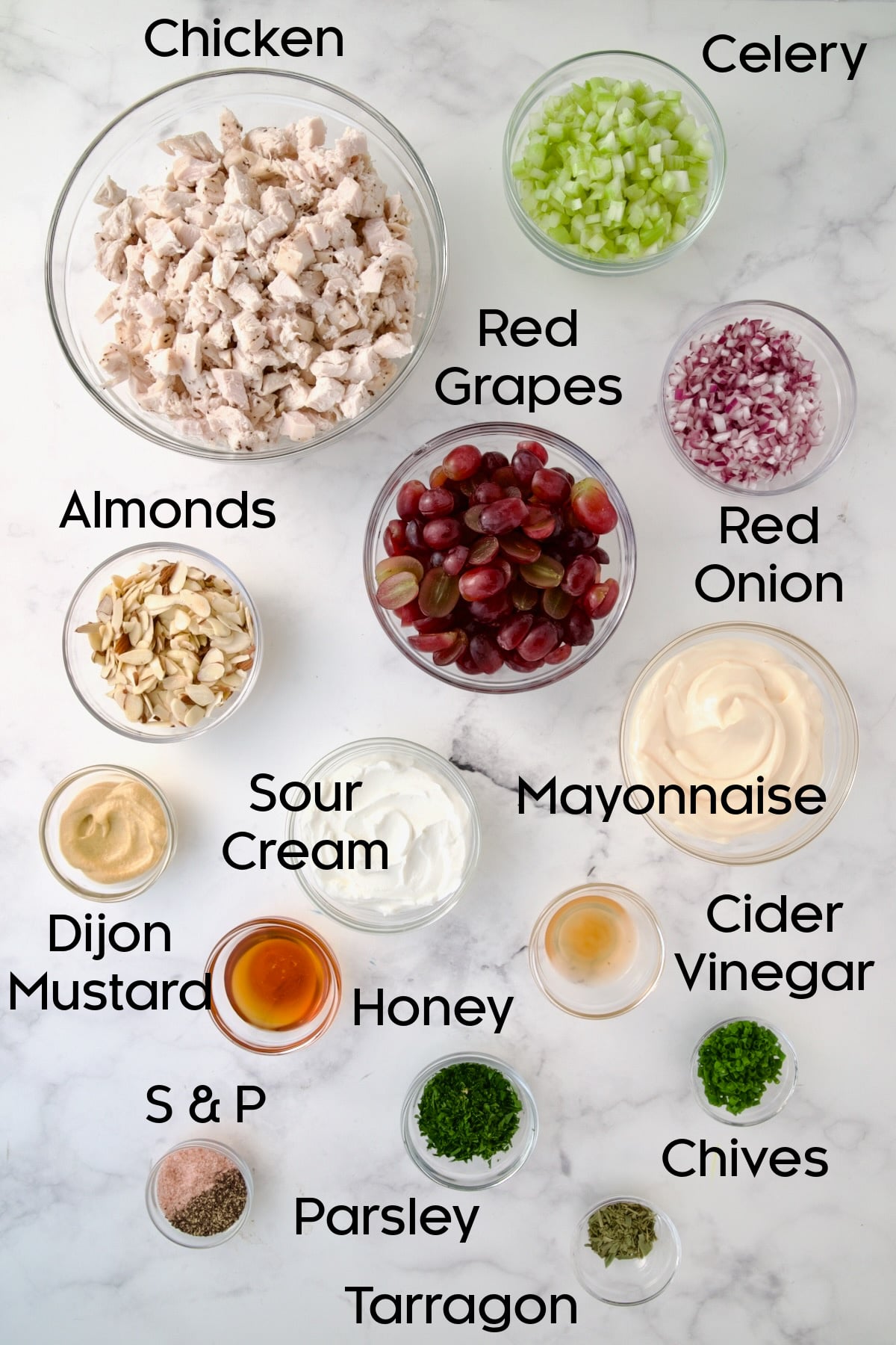 Ingredients for Chicken Salad with Herbs, Almonds and Grapes in glass bowls.