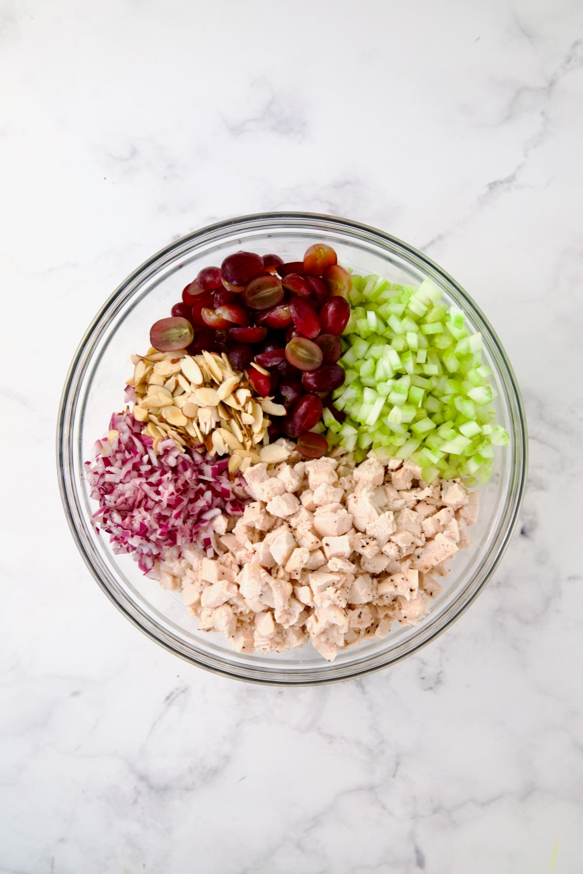 Chicken salad ingredients in glass bowl before mixed together.