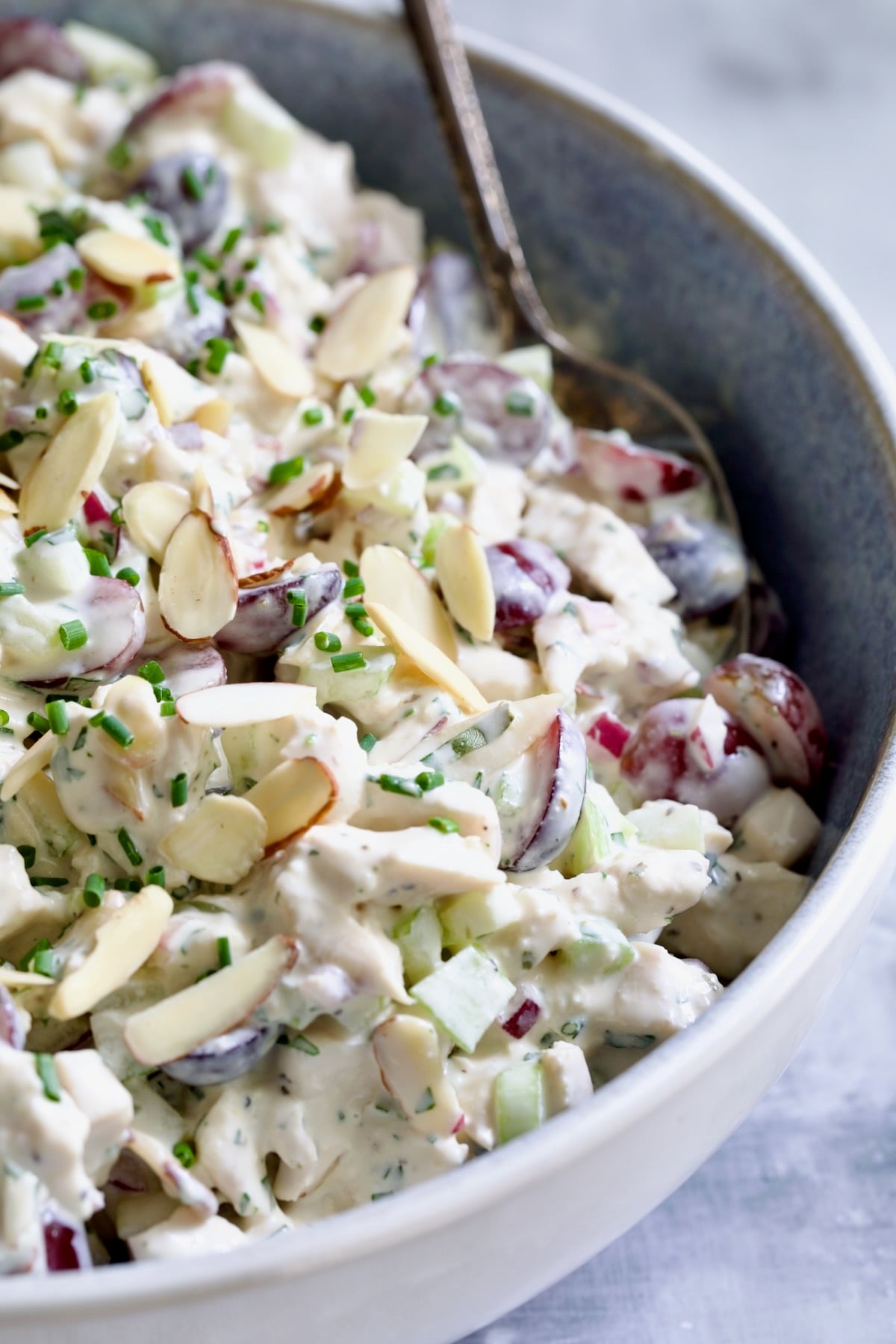 Chicken salad in blue bowl with serving spoon.