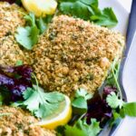 Crispy Chickpea-Crusted Fish on oval white platter garnished with fresh baby greens.