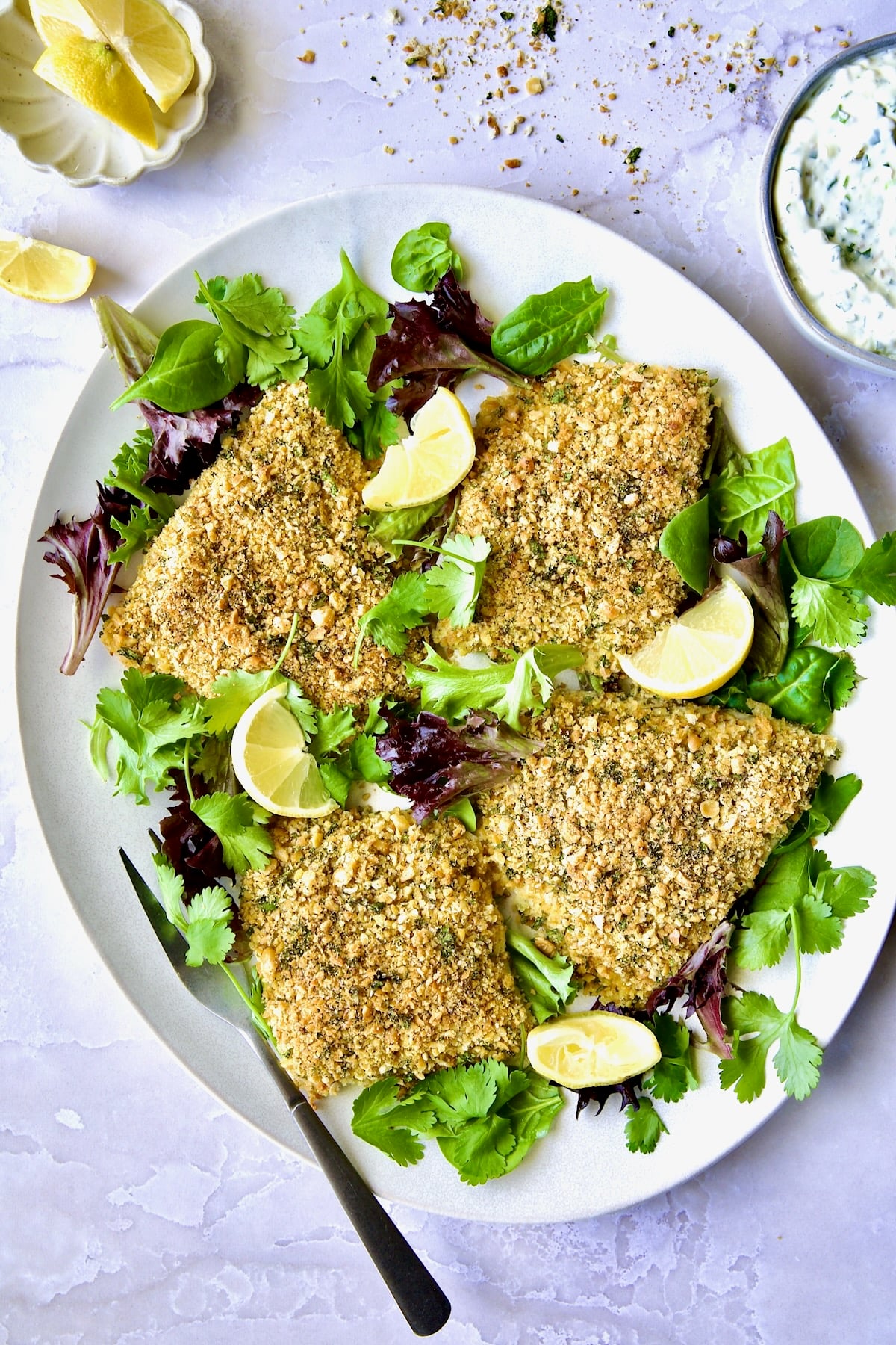 Crispy Chickpea-Crusted Fish on oval white platter garnished with fresh baby greens.