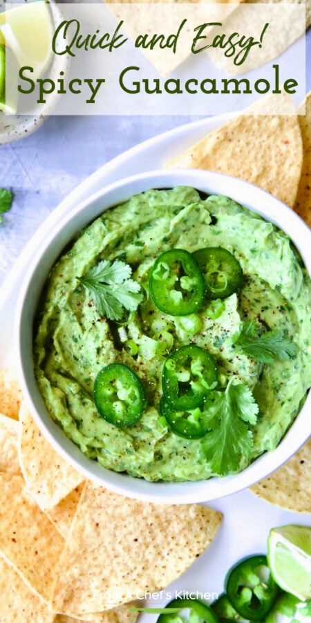 Pinterest graphic for Spicy Guacamole showing it in a white bowl surrounded by tortilla chips, garnished with jalapeno slices and cilantro leaves.