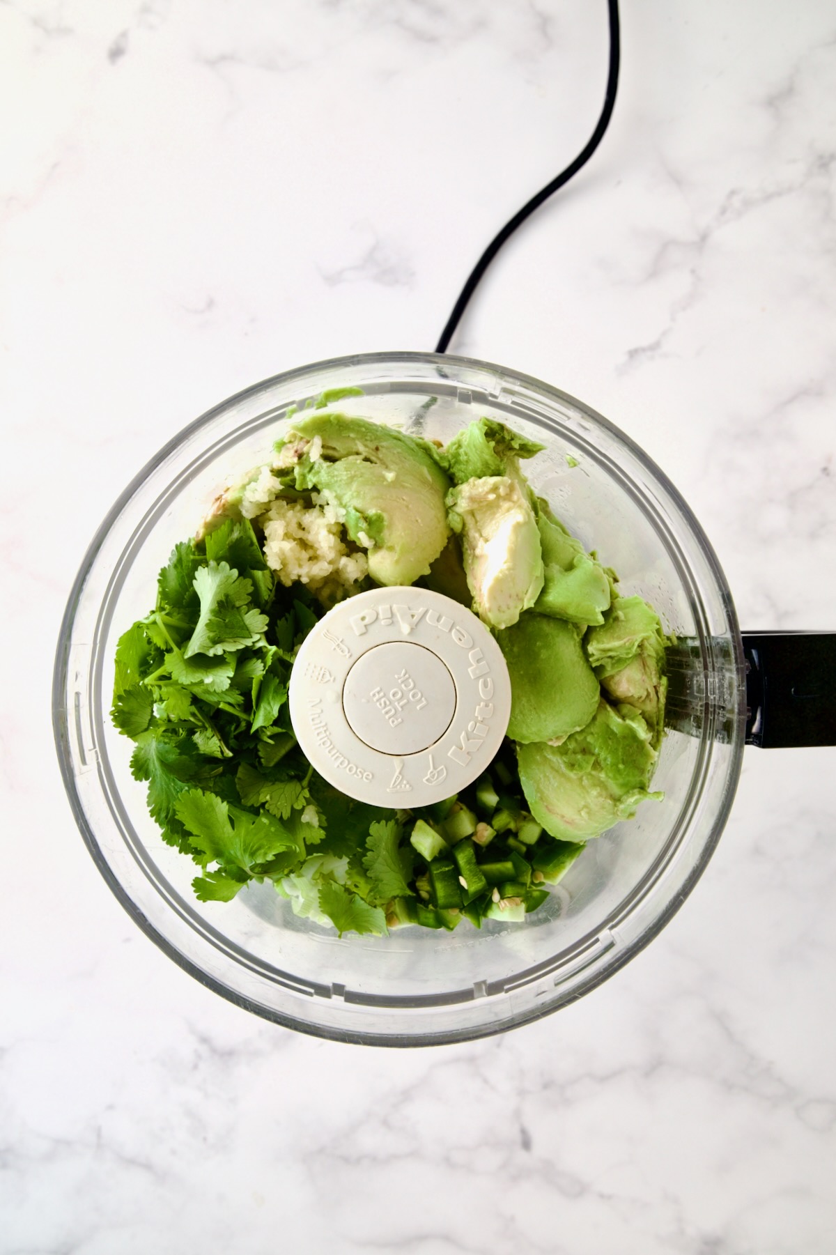Ingredients for guacamole in food processor before being combined.