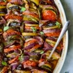 Briam (Greek Roast Vegetables) in oval white gratin dish with serving spoon.