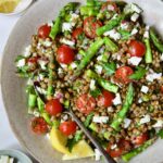 Lemony Lentil Salad with Asparagus and Tomatoes in round earthenware serving bowl with serving