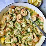 Shrimp Scampi with Artichokes in white enamel cast iron pan with serving spoon.