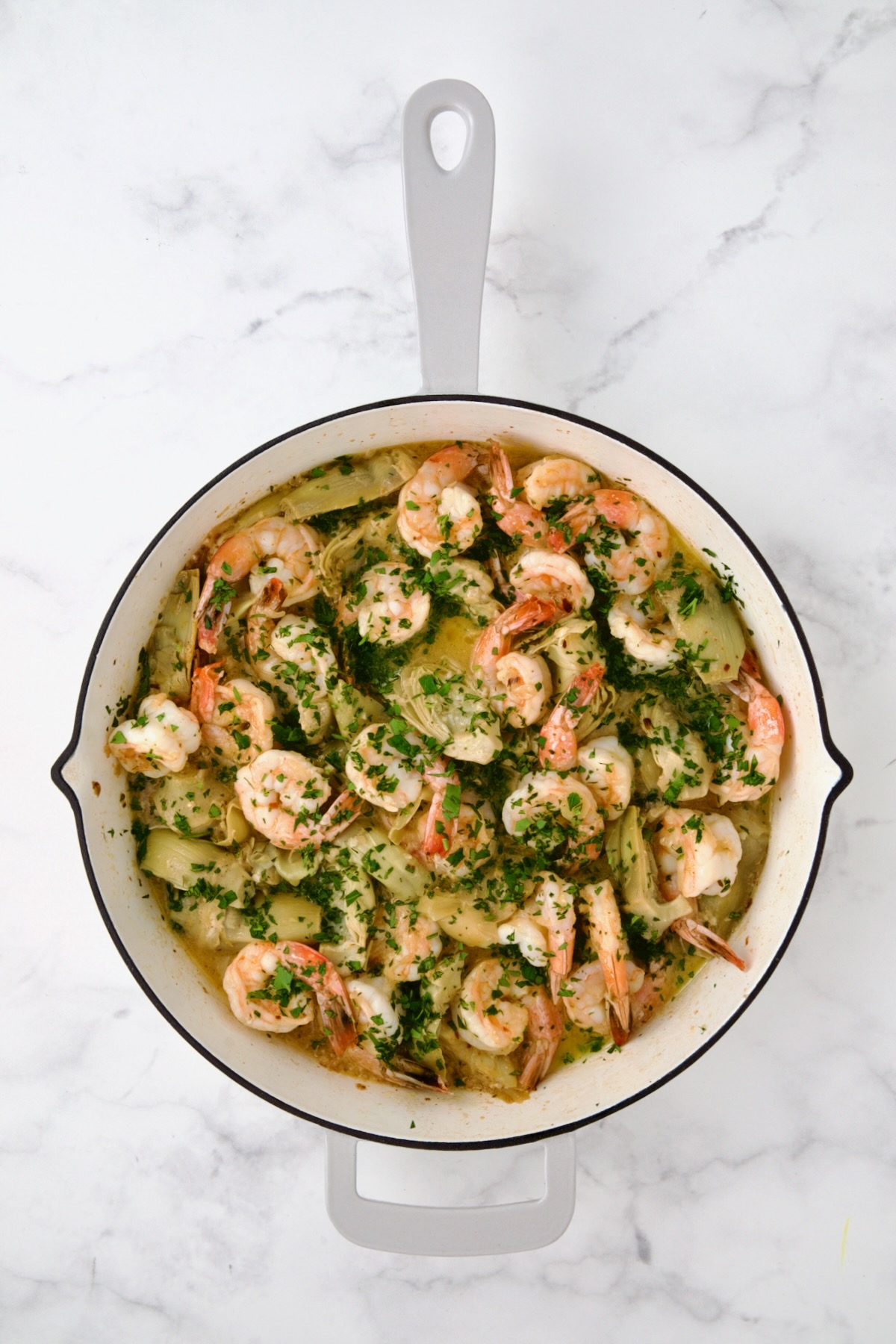 Finished Shrimp Scampi with Artichokes in white enamel cast iron pan.