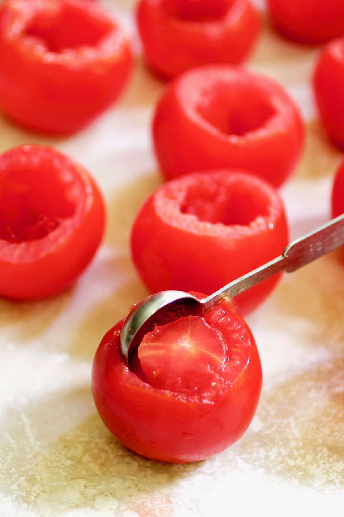 Teaspoon removing the center of Campari tomatoes.