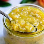 Peach Jalapeno Chutney in a glass jar with a spoon holding some to show detail.