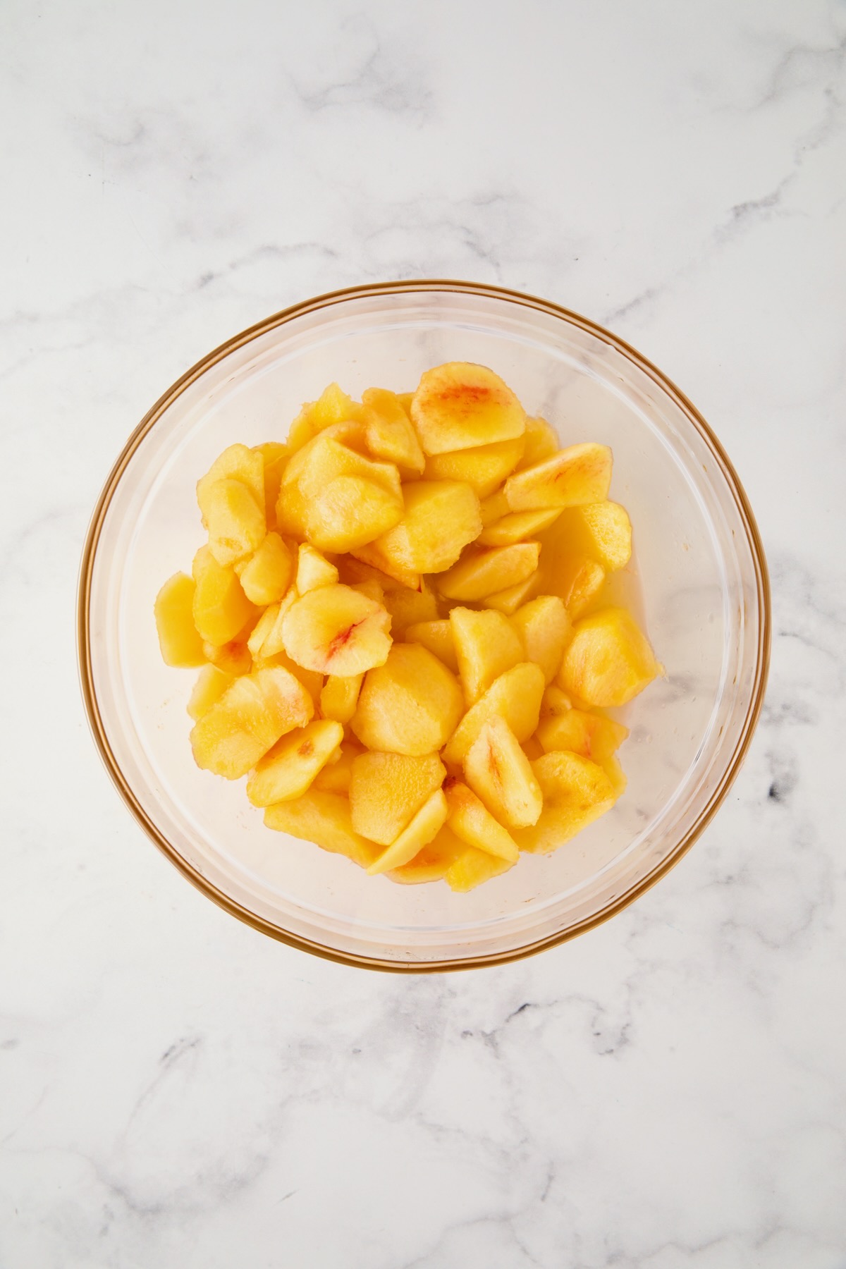 Peeled peach chunks in glass bowl.