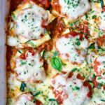 Zucchini Ravioli in white baking dish with serving spoon.