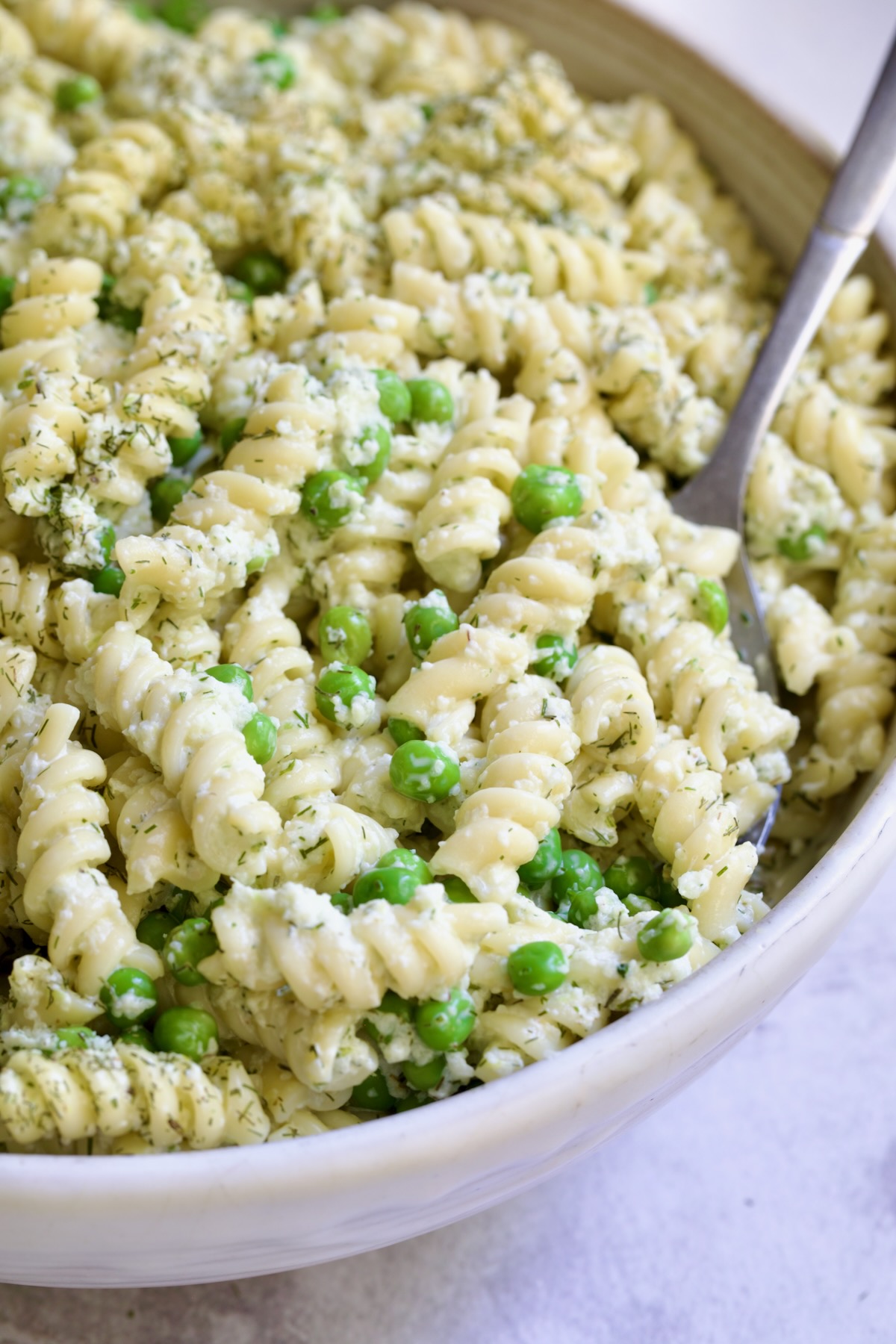 Creamy Cucumber Pasta Salad in white serving bowl with serving spoon.