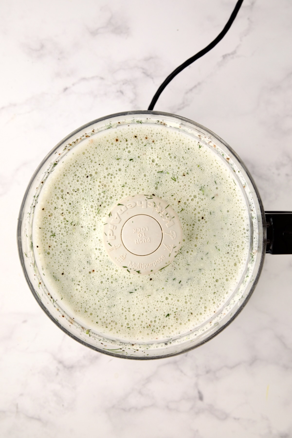 Ingredients for salad dressing in a food processor after being blended together.