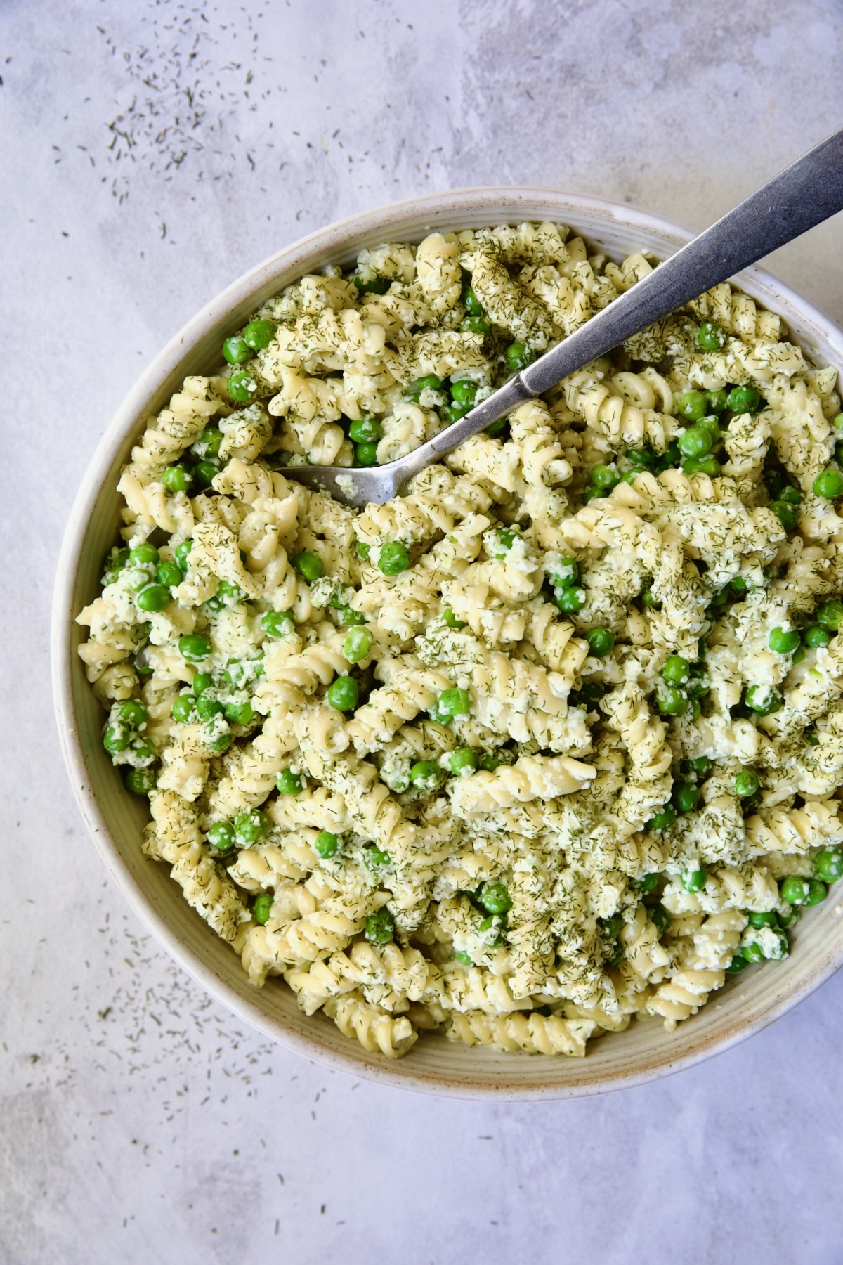 Creamy Cucumber Pasta Salad in white serving bowl with serving spoon.