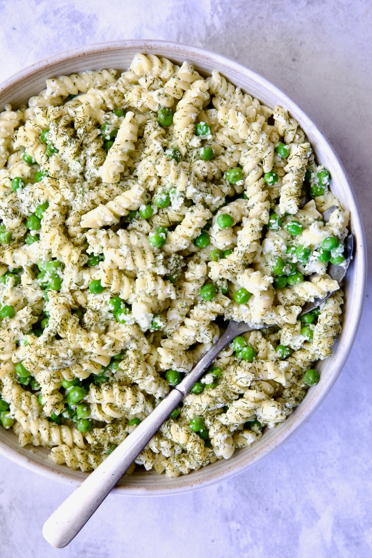 Creamy Cucumber Pasta Salad in white serving bowl with serving spoon.