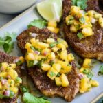 Three Pork Chops with Peach Salsa on oval gray platter.