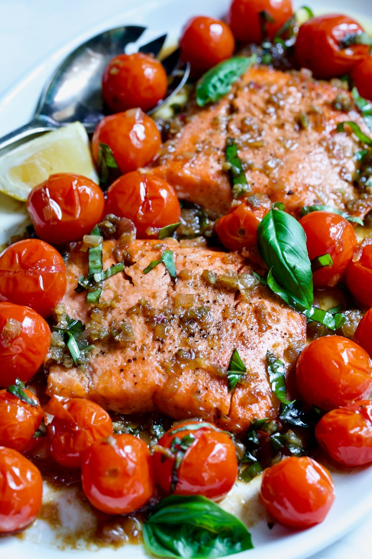 Salmon with Balsamic Cherry Tomatoes on oval white platter with serving fork.