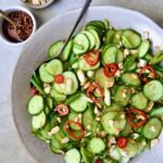 Spicy Asian Cucumber Salad in earthenware bowl with serving spoon garished with peanuts.