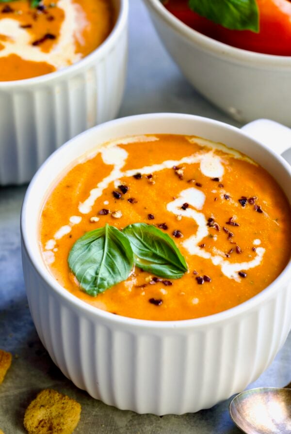 Creamy Tomato and Basil Soup in a white soup mug garnished with fresh basil leaves.