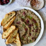 Eggplant Caviar (Caviar d'Aubergine) in white bowl with five pieces of grilled bread on the side.
