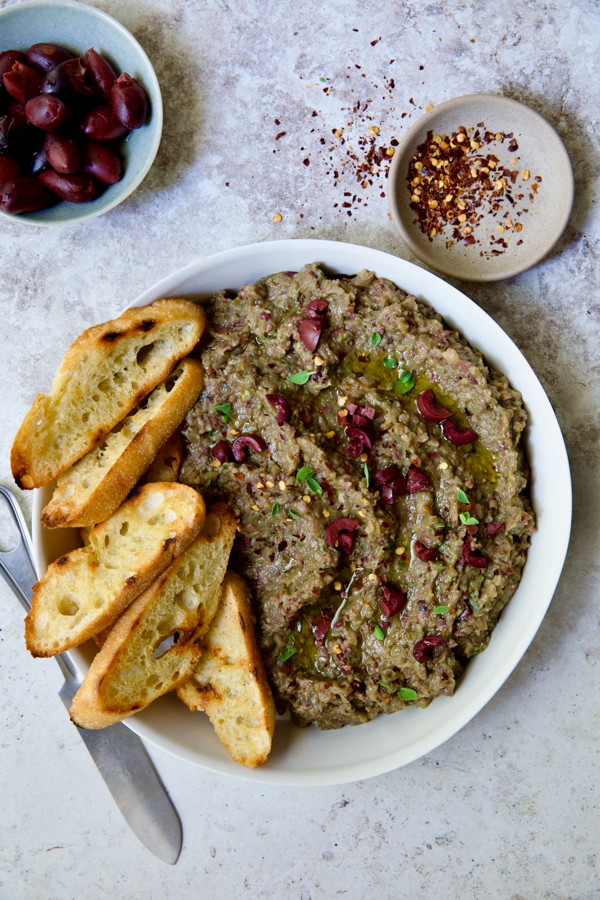 Eggplant Caviar (Caviar d'Aubergine) in white bowl with five pieces of grilled bread on the side.