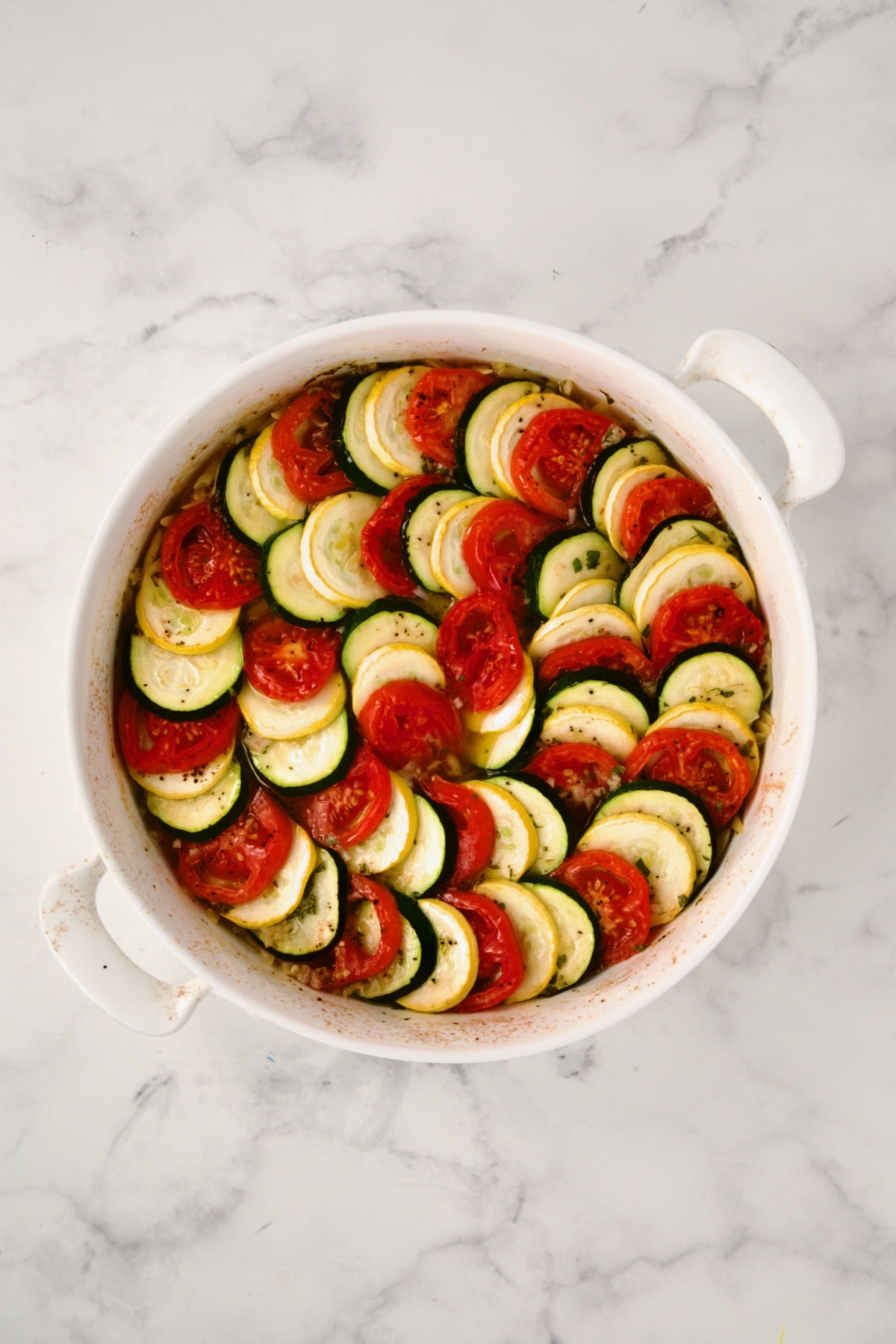 Partially baked tian in round white baking dish.
