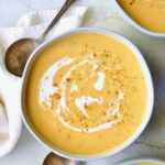 Three servings of Butternut Squash Brie Soup in white bowls.