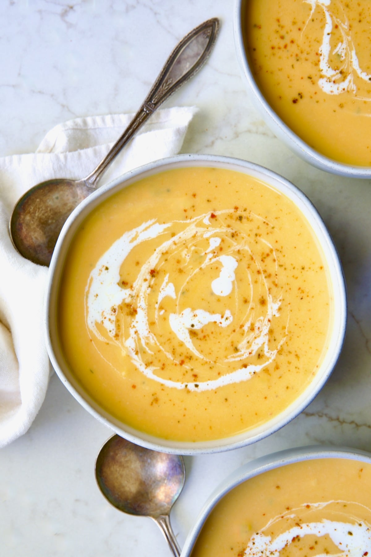 Three servings of Butternut Squash Brie Soup in white bowls.
