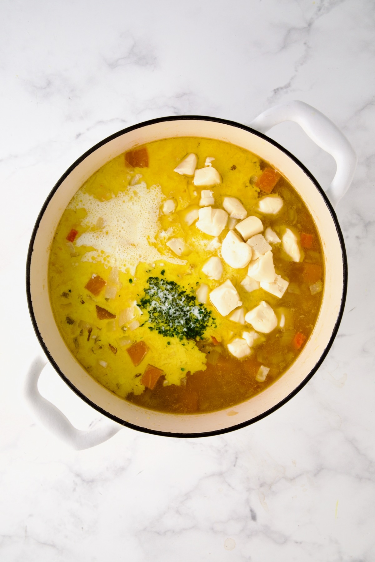 Brie, cream and chopped fresh thyme added to vegetables and broth in white enamel cast iron skillet.