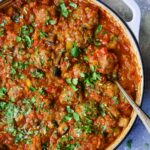 Moroccan Meatball Stew in white enamel cast iron skillet with serving spoon.