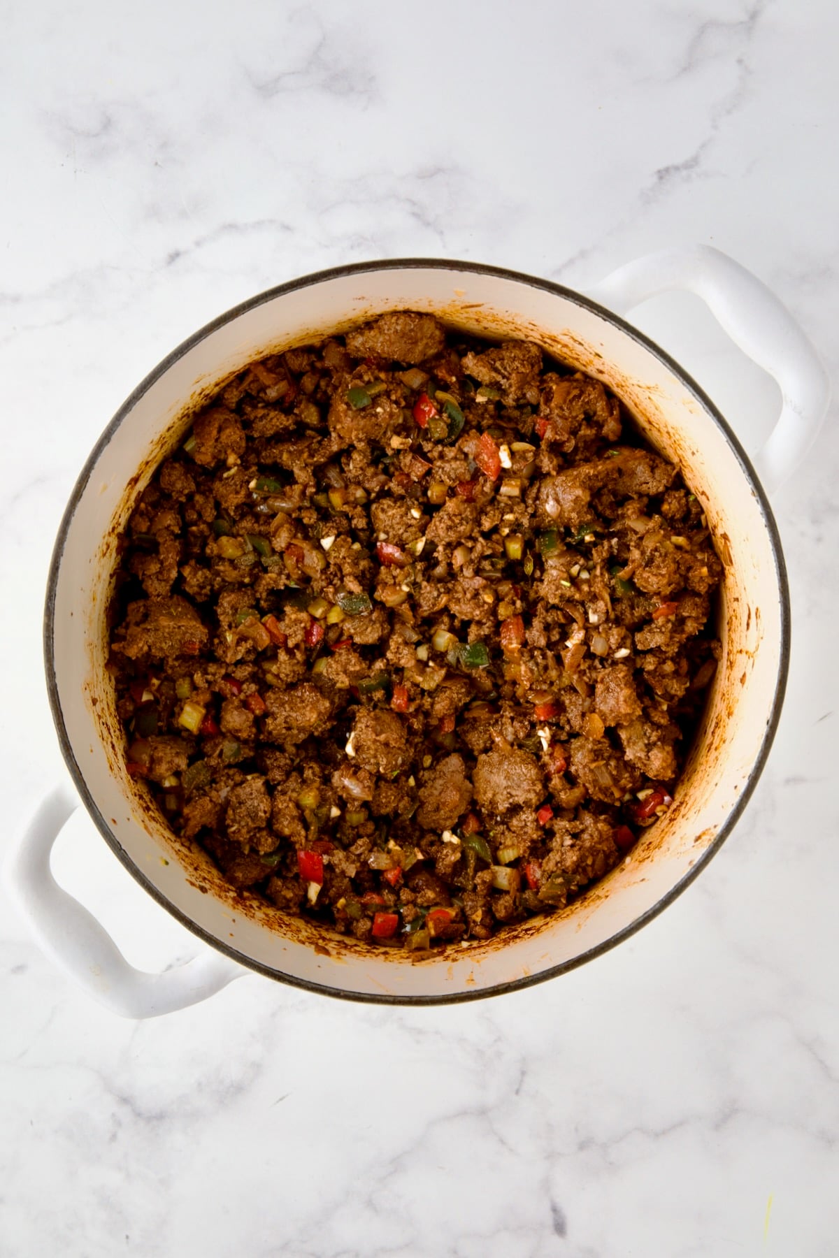 Beef and pork added back to white enamel Dutch oven with spices, vegetables and wine.