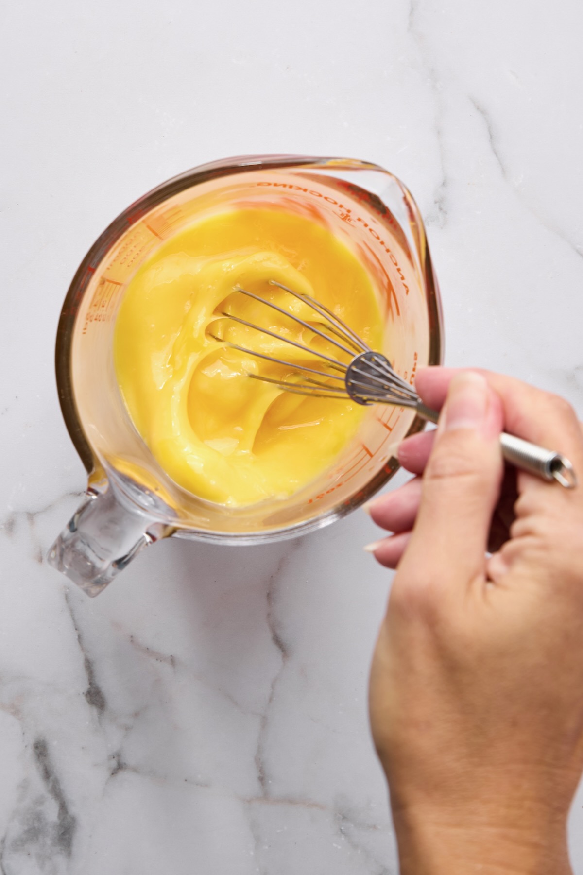 Eggs being blended in glass measuring pitcher.