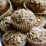 Stack of Pumpkin Streusel Muffins on napkin-lined basket.