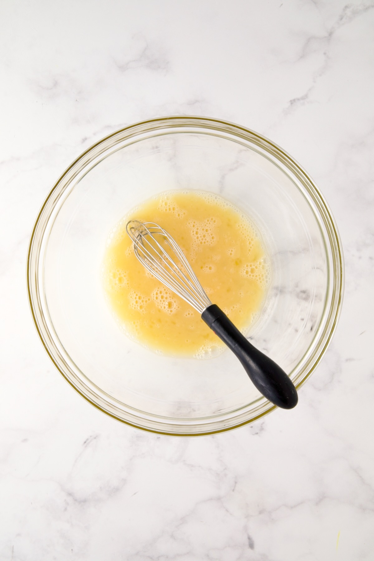 Egg whites and whole egg in glass bowl.