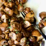 Garlic Butter Mushrooms on oval white platter with black dinner fork.