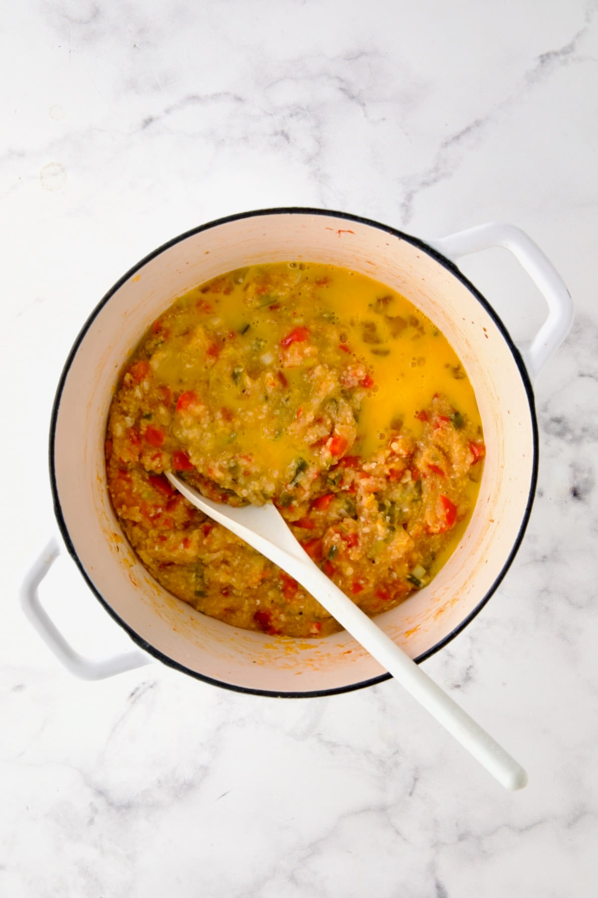 Egg added to vegetable and grits combination before being stirred in.