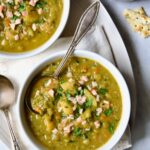 Two servings of Slow Cooker Split Pea Soup in white bowls on white oval platter.