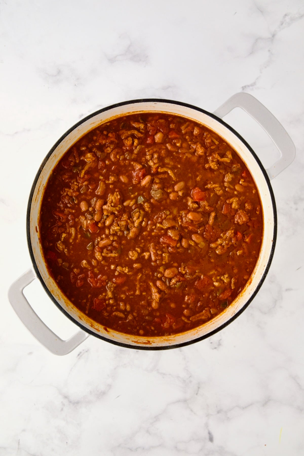 Cooked Turkey Skillet Chili in white enamel cast iron skillet read to be topped with biscuits.
