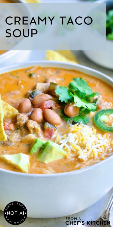 Pinterest graphic for Creamy Taco Soup showing one serving in a white bowl garnished with tortilla chips, avocado, jalapeno and cilantro.