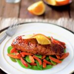 Pomegranate and Orange-Glazed Salmon with Stir-Fried Vegetables on white plate.