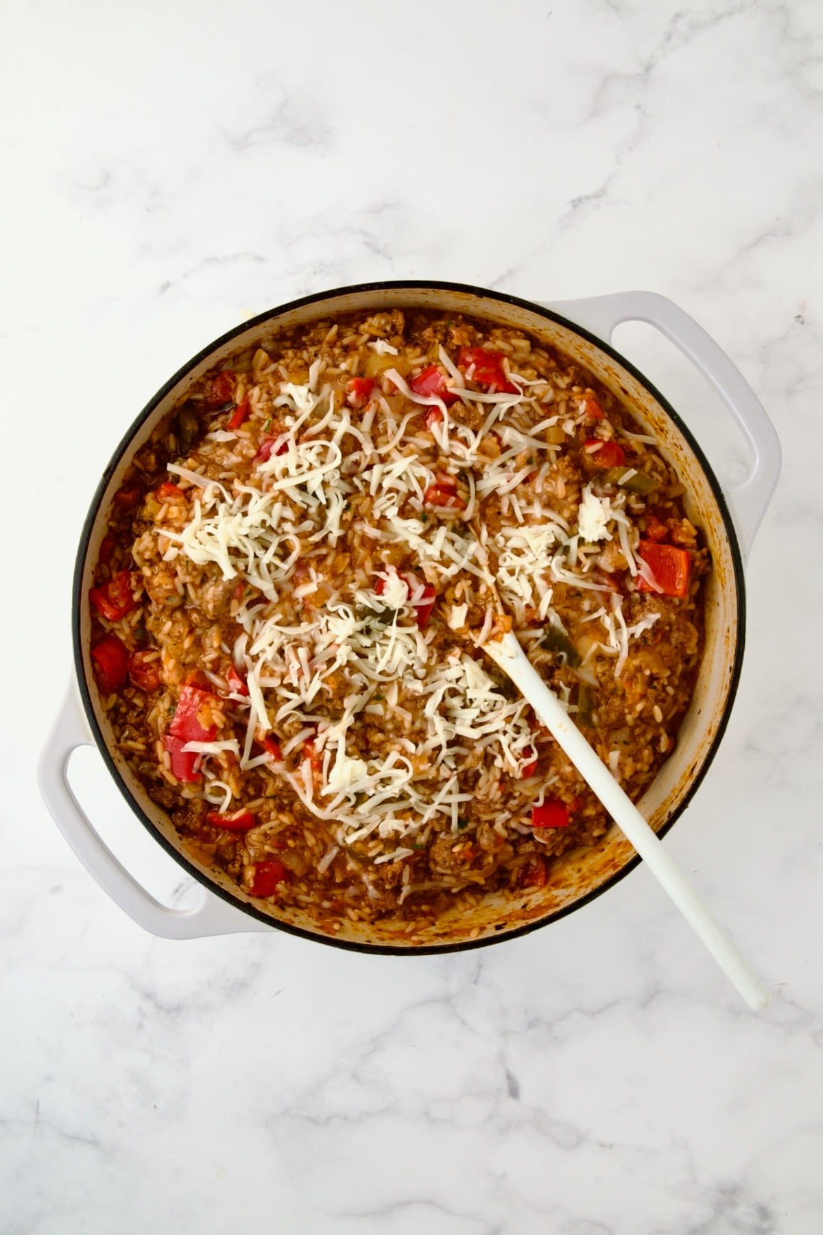Cheese stirred into finished dish in white enamel cast iron skillet.