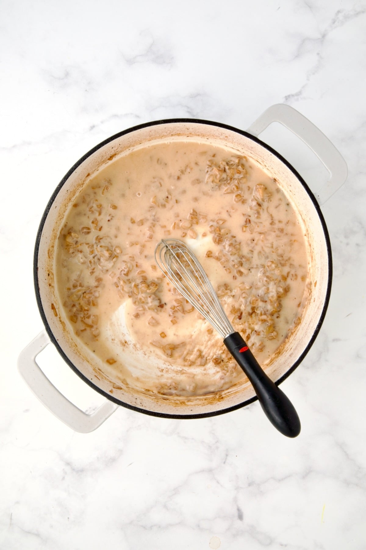 Dry white wine, onions and flour smoothed out in white enamel casit iron skillet.