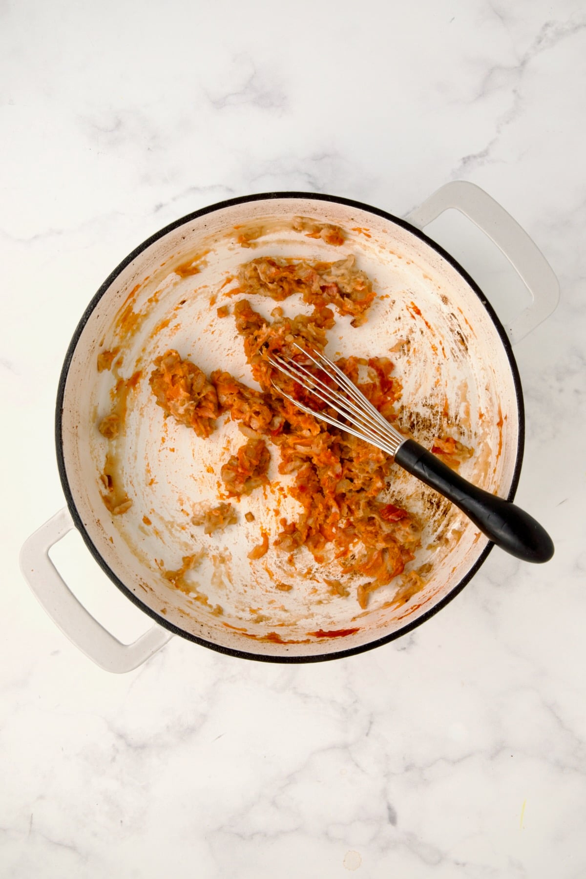 Tomato paste added to wine, onions and flour in white enamel cast iron skillet.
