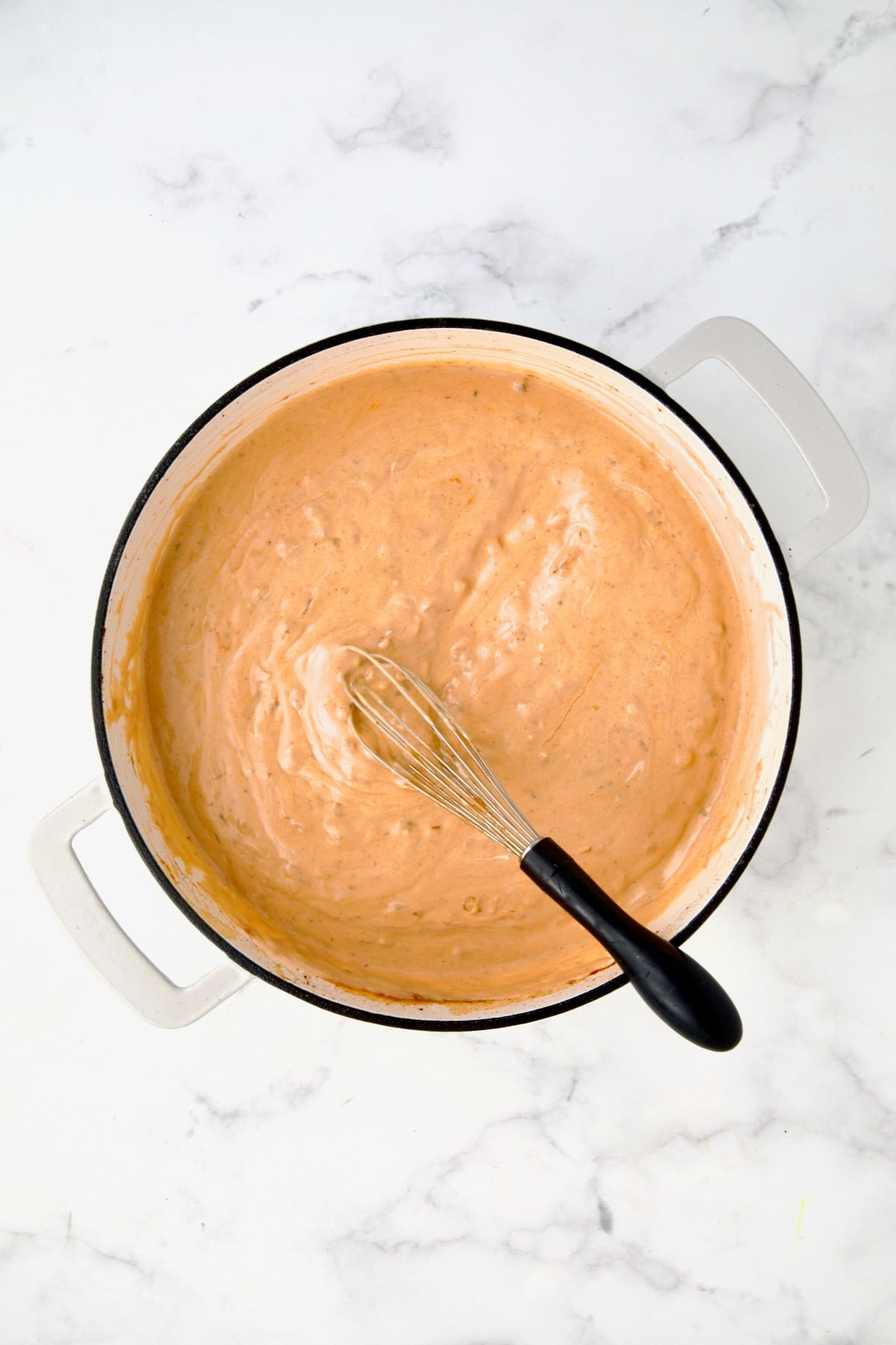 Fully combined and thickened sauce in white enamel cast iron skillet.