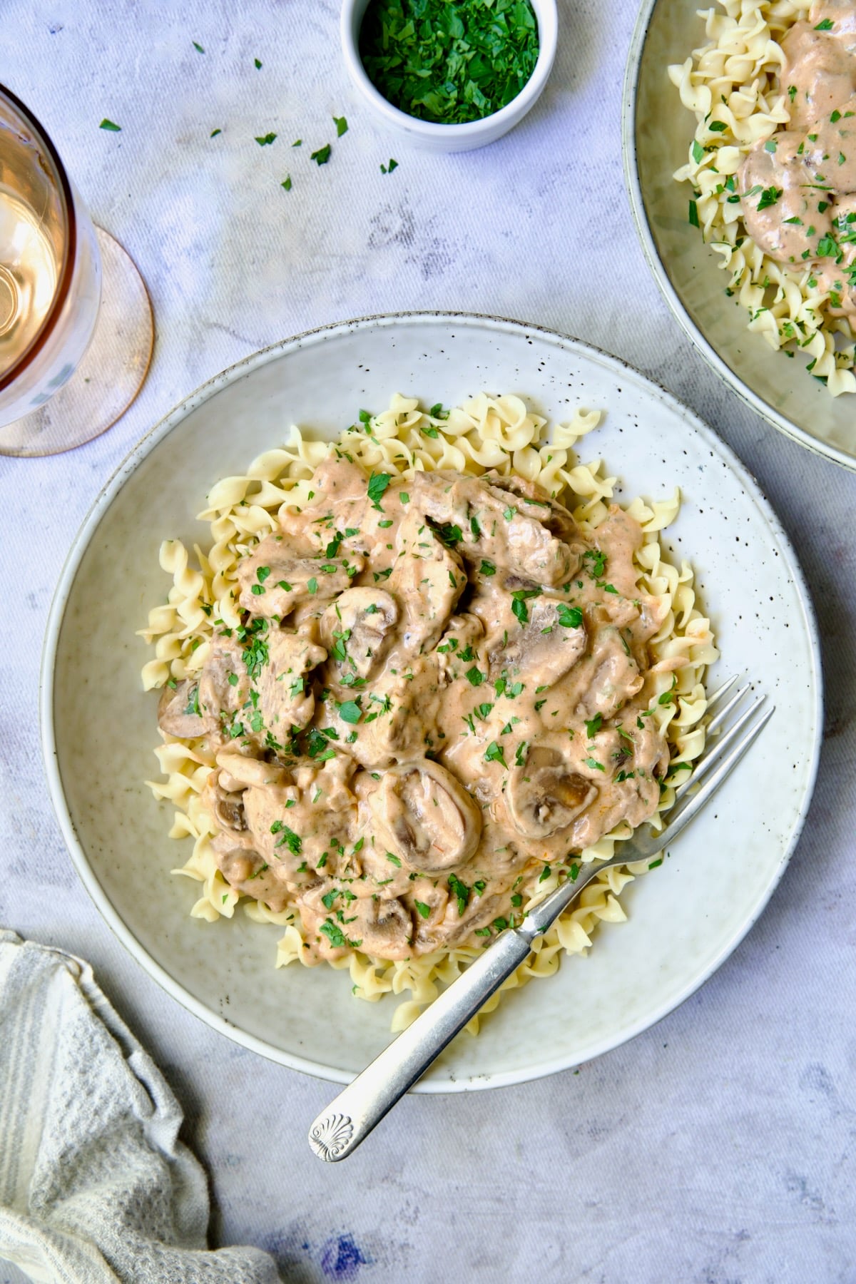 Date Night Beef Stroganoff over curly egg noodles in dinner bowl with dinner fork.