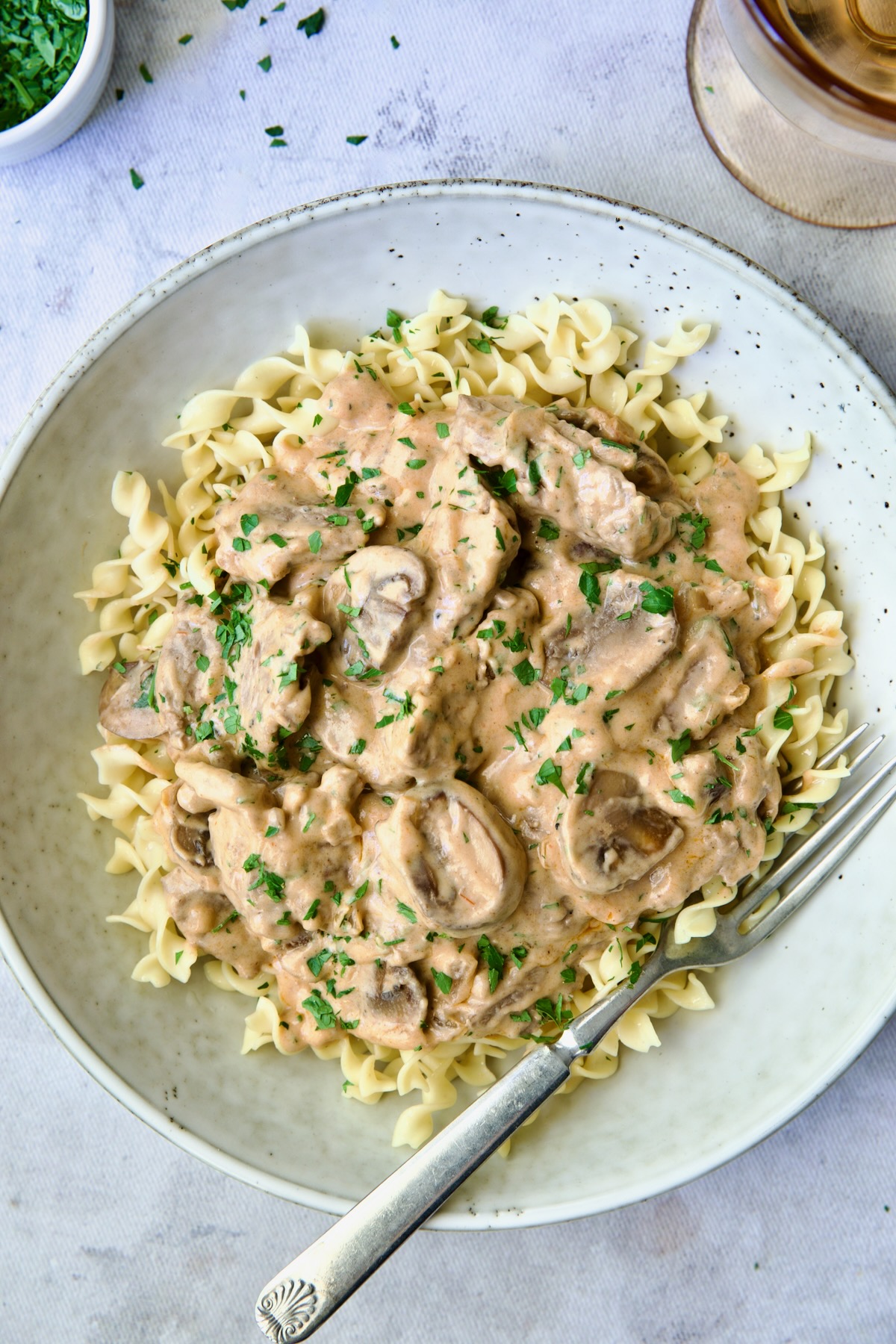 Date Night Beef Stroganoff over curly egg noodles in dinner bowl with fork.