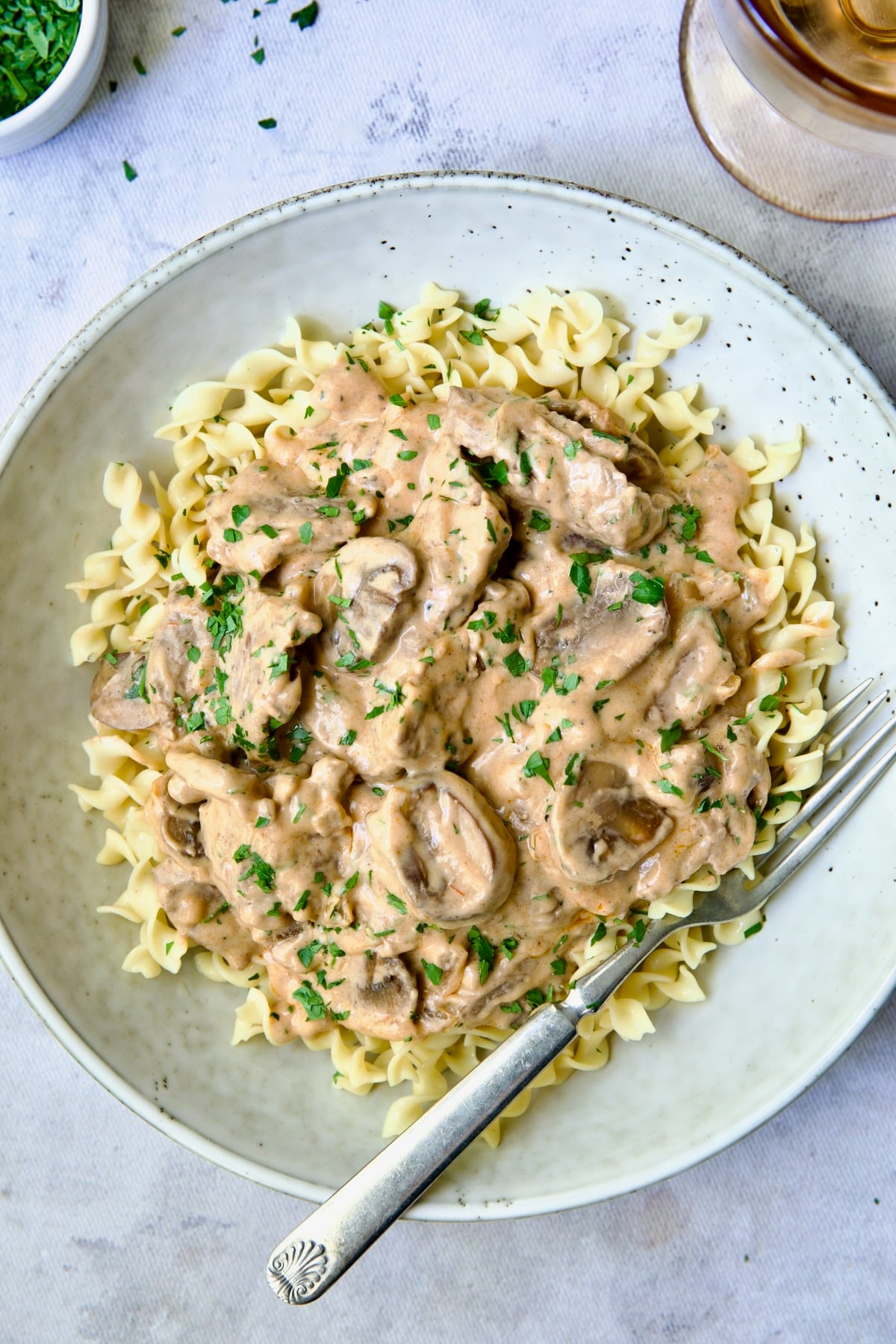 Date Night Beef Stroganoff over curly egg noodles in dinner bowl.