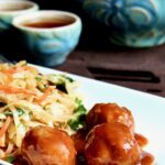 Three Asian Pork Meatballs on white plate with noodles.